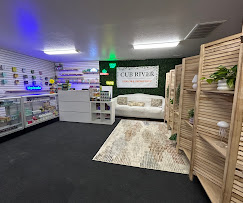Inside Cub River Kratom & Smoke Shop: neon-lit interior with a white couch, wood shelving, and product displays